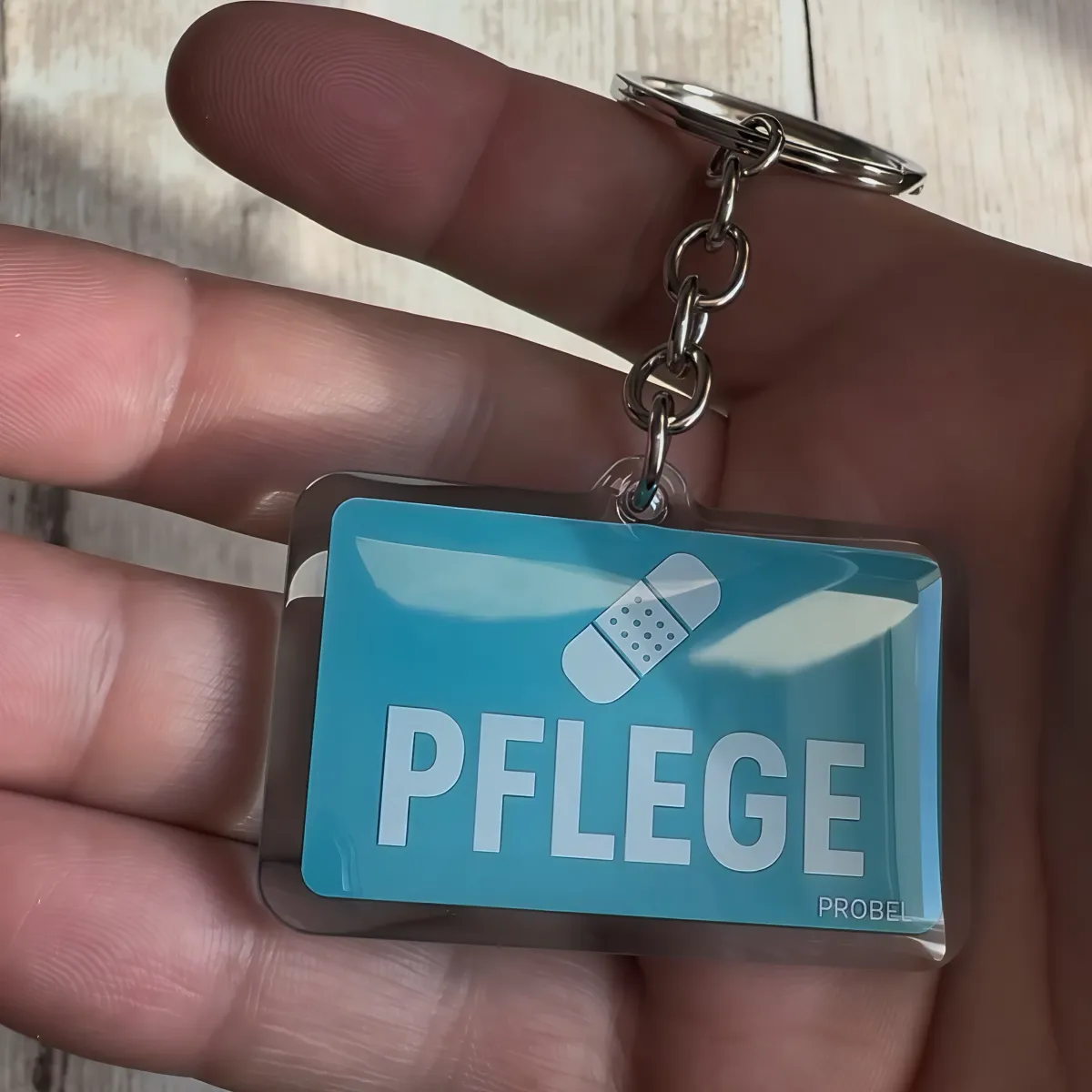 Acryl-Schlüsselanhänger "Pflege" mit Pflaster-Symbol